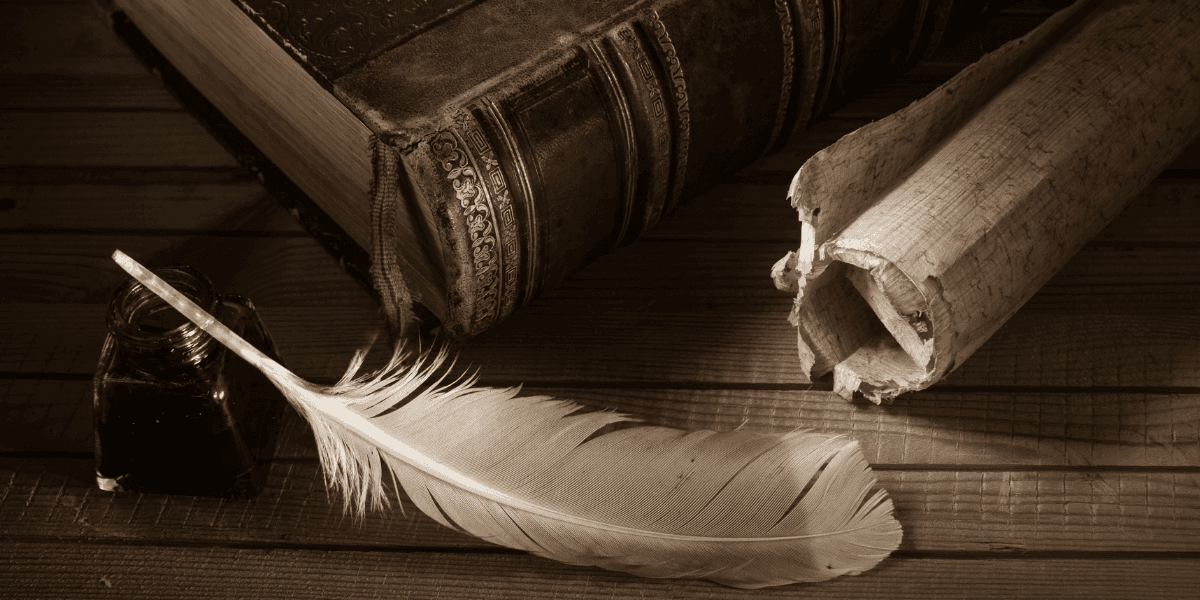 Antique book, feather quill, ink bottle, and rolled parchment on a wooden table
