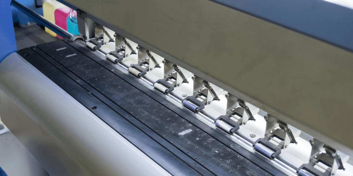 Close-up of a printing machine's ink rollers and feed mechanism in operation
