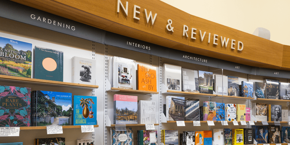 Books displayed on shelves under "New & Reviewed" signage in various categories
