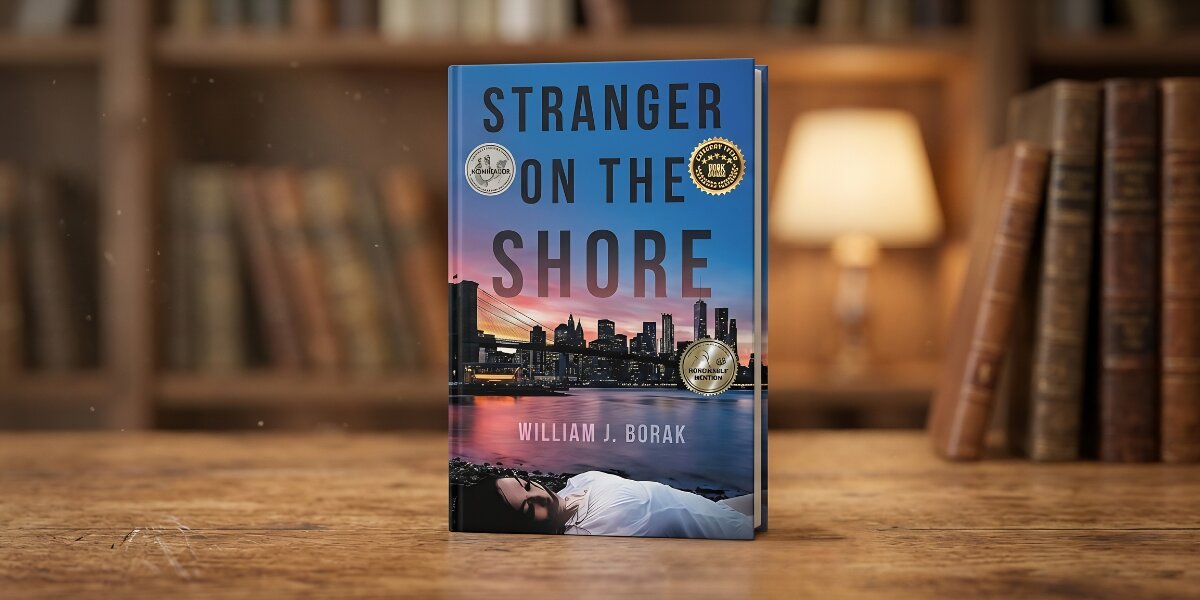 A book titled "Stranger on the Shore" by William J. Borak is displayed on a wooden table. The cover features a city skyline at sunset and a woman lying down. The background includes blurred bookshelves and a warm lamp, suggesting a cozy library setting.