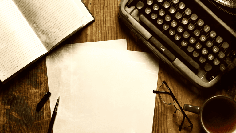 Typewriter, blank paper, notebook, pen, glasses, and coffee cup on wooden table