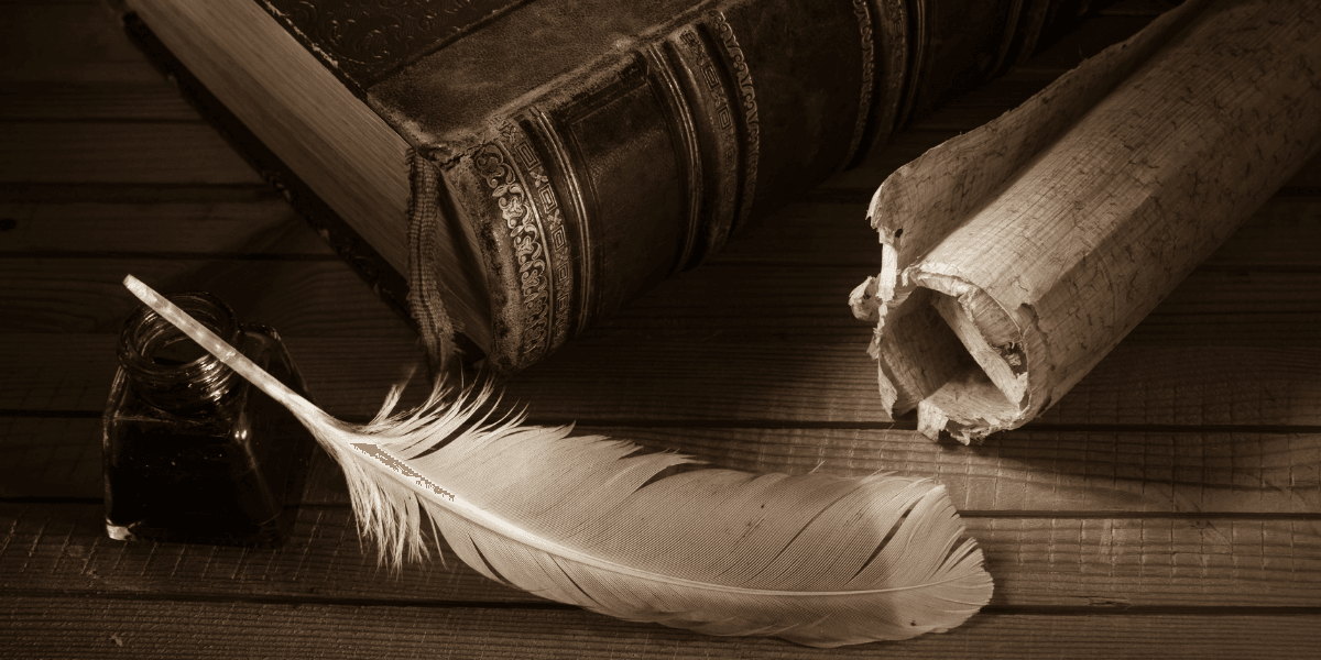 Antique book, feather quill, ink bottle, and rolled parchment on a wooden table