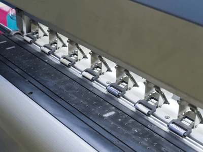 Close-up of a printing machine's ink rollers and feed mechanism in operation