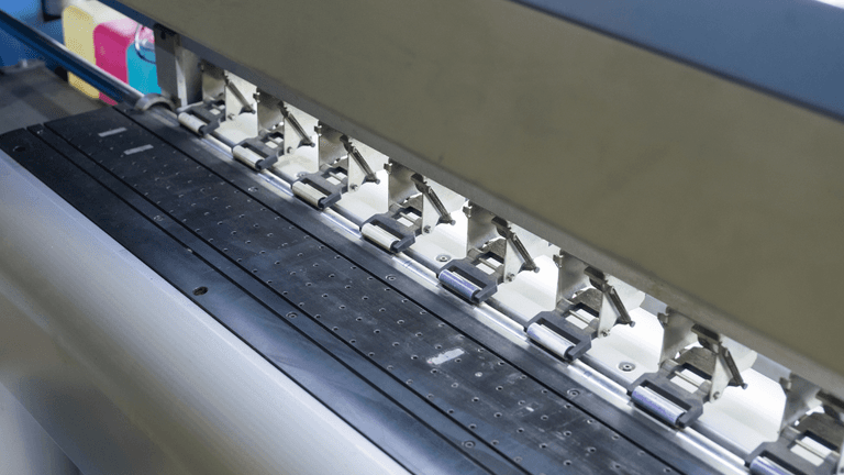 Close-up of a printing machine's ink rollers and feed mechanism in operation