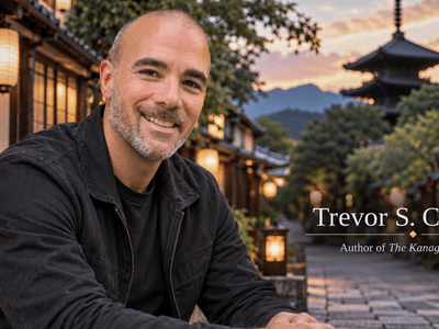A smiling man sits outdoors in a picturesque traditional setting with lanterns.