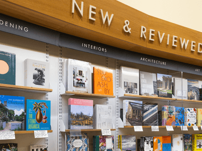 Books displayed on shelves under "New & Reviewed" signage in various categories