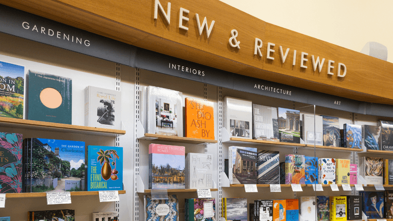 Books displayed on shelves under "New & Reviewed" signage in various categories