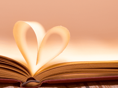 An open book with pages forming a heart shape in soft light