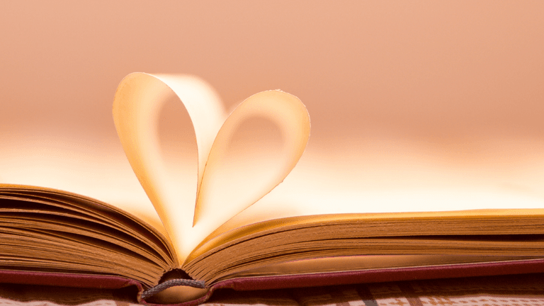 An open book with pages forming a heart shape in soft light