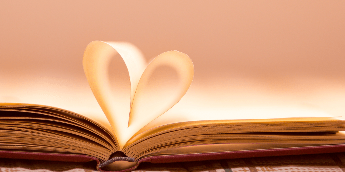 An open book with pages forming a heart shape in soft light