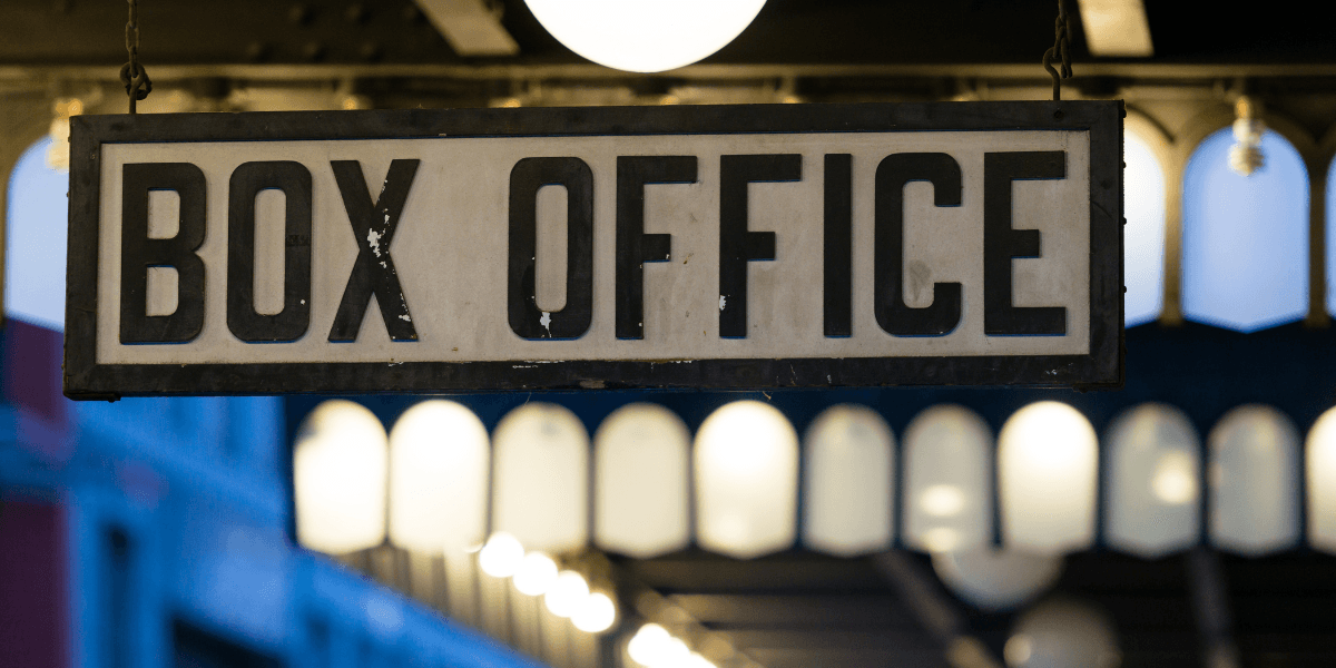 Vintage hanging sign displaying "BOX OFFICE" inside a theater lobby.