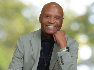 Portrait of Dr. Alvin Haywood smiling in a light gray blazer with a cross necklace.