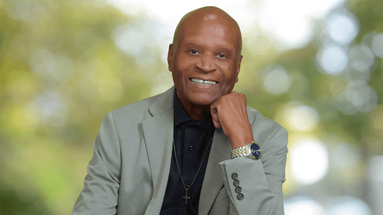 Portrait of Dr. Alvin Haywood smiling in a light gray blazer with a cross necklace.