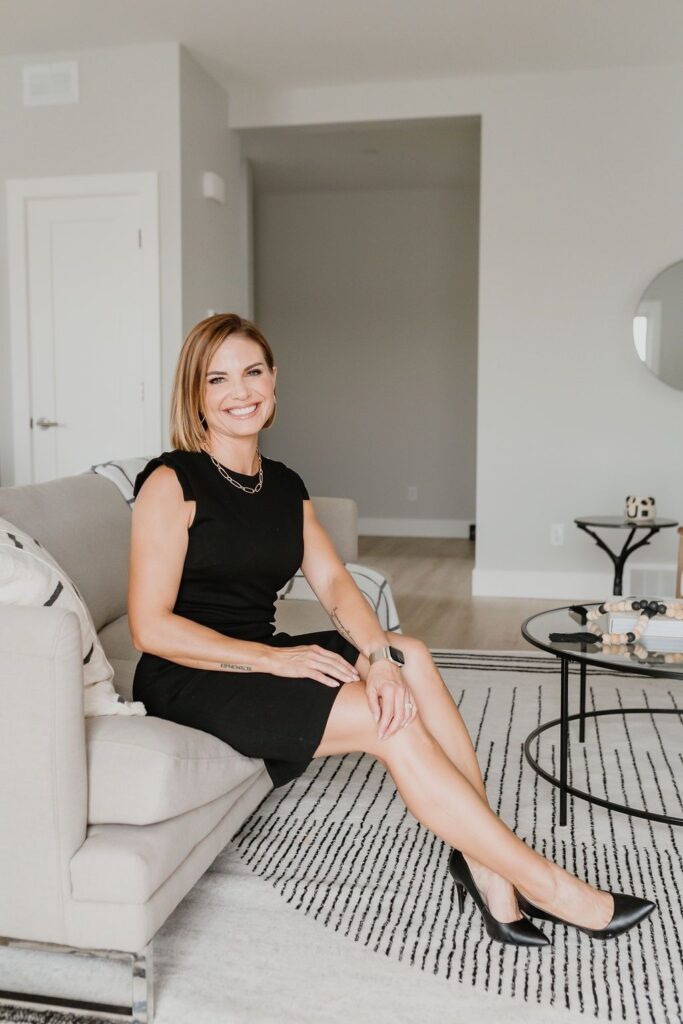 Angela Porrelli seated on a sofa in a modern living room wearing a black dress.